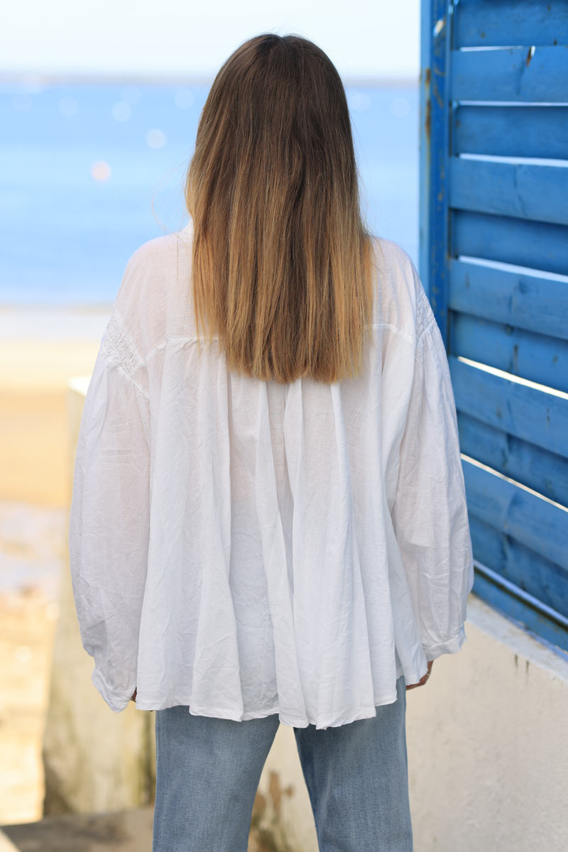 Blusa blanca de algodón con mangas anchas, botones nacarados y cuello fruncido.
