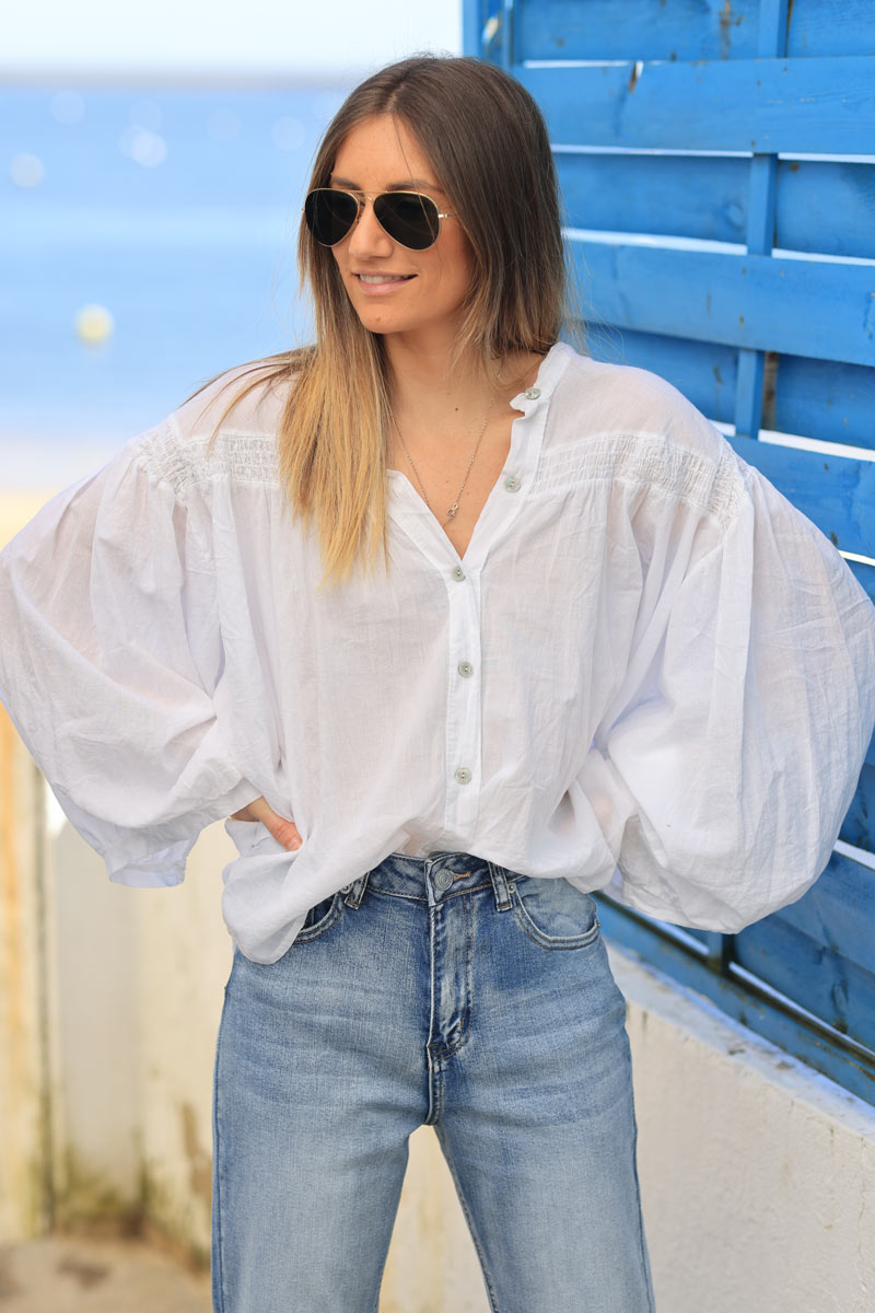 Blusa blanca de algodón con mangas anchas, botones nacarados y cuello fruncido.