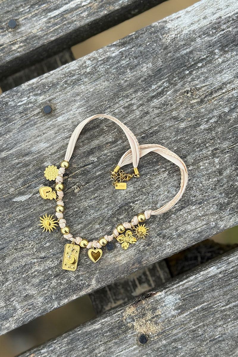 Collier ruban beige et pendentifs dorés trèfle soleil cœur et lune