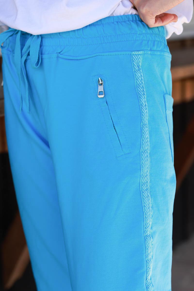 Pantalón de jogging de algodón azul con cinturilla elástica y bolsillos con cremallera con ribete de bordado de espiga