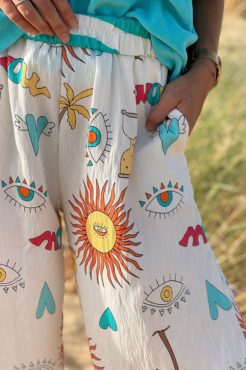 Pantalon fluide écru symboles soleil œil et cœurs colorés turquoise