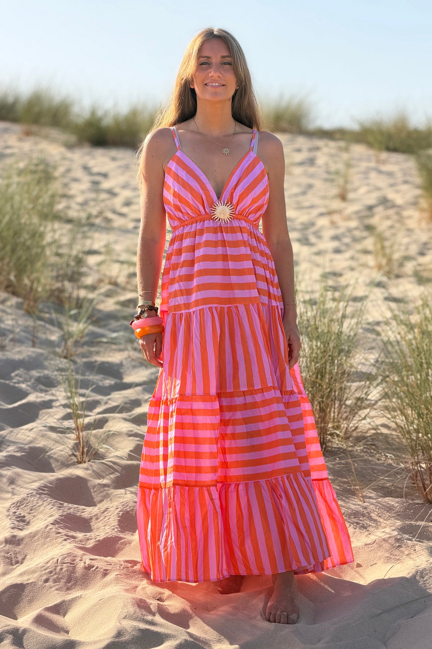 Robe longue à bretelles en coton motifs rayures orange et rose broche soleil doré