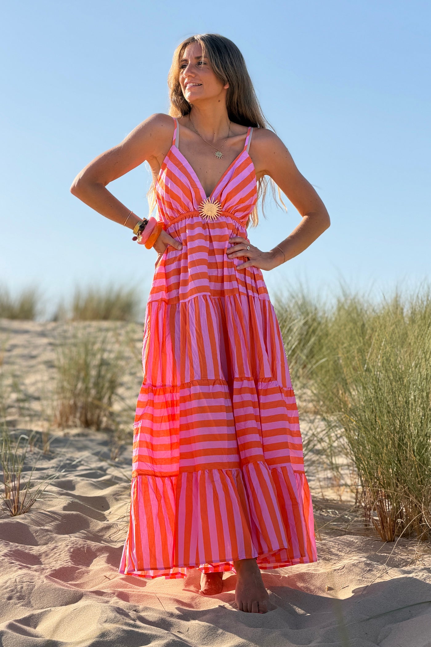 Robe longue à bretelles en coton motifs rayures orange et rose broche soleil doré