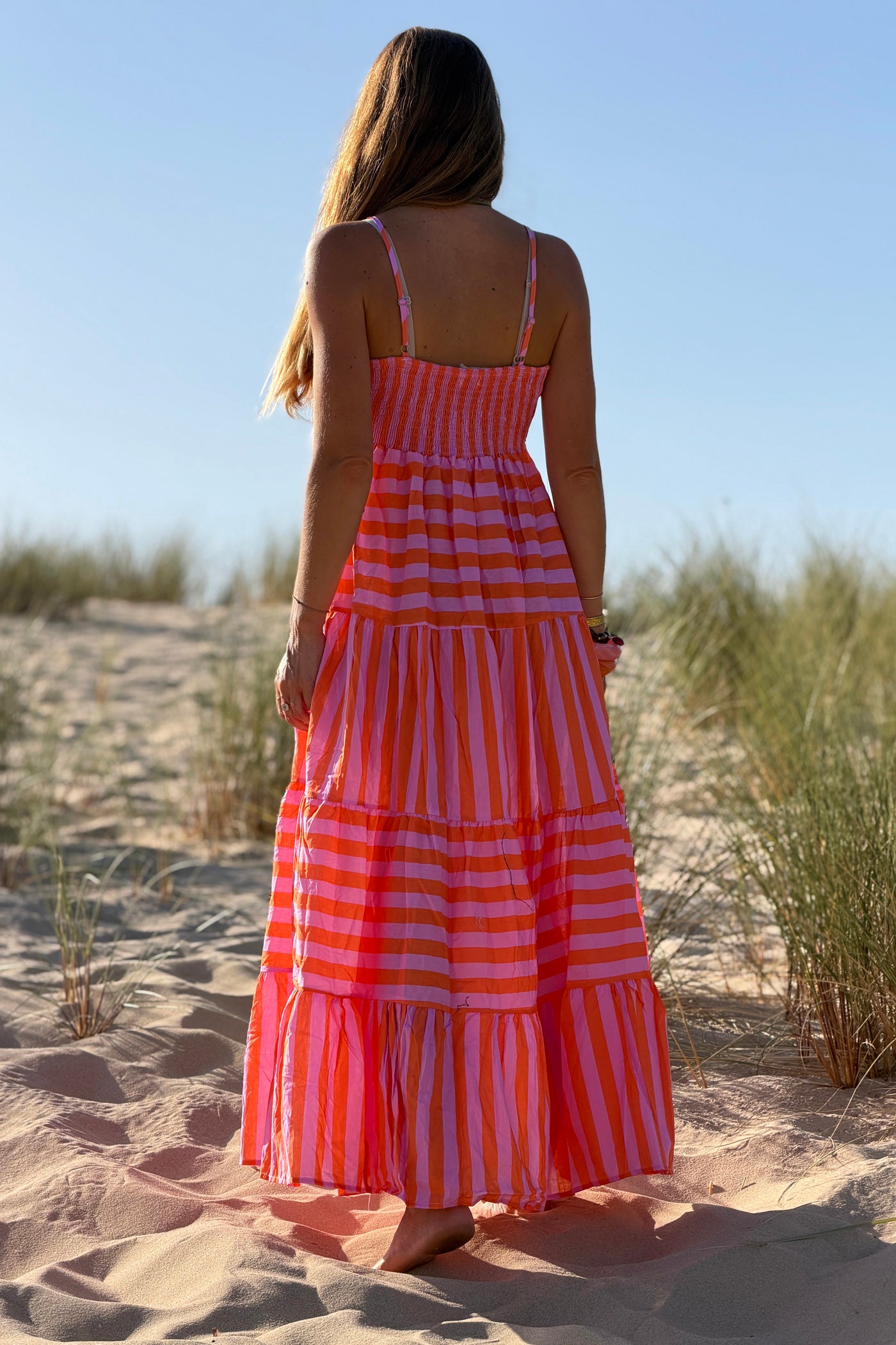 Robe longue à bretelles en coton motifs rayures orange et rose broche soleil doré