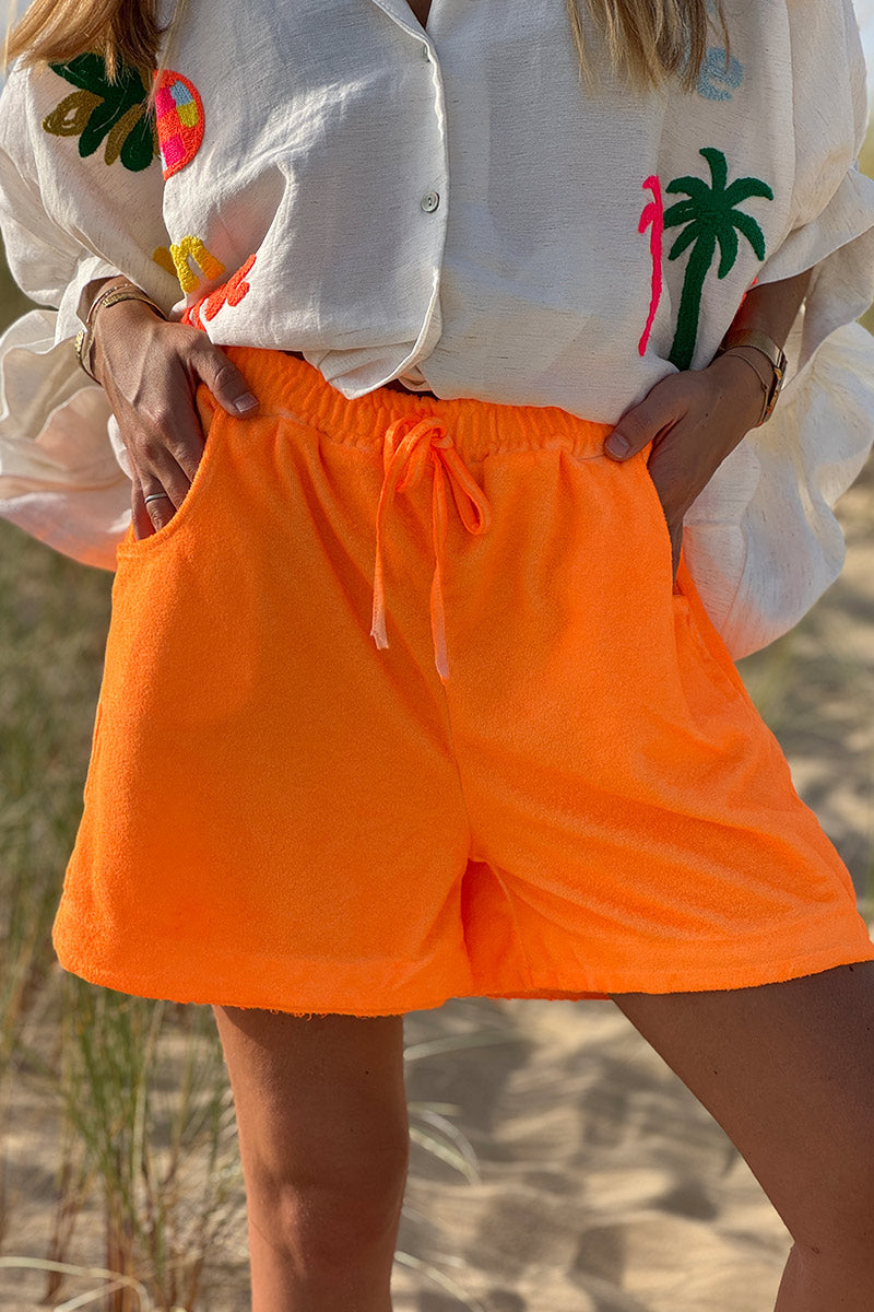 Shorts cómodos de color naranja fluorescente en suave tejido de rizo con cinturilla elástica.