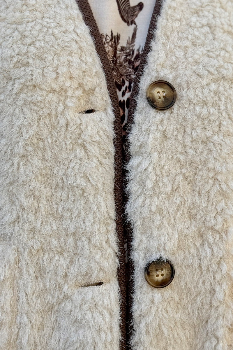 Veste sans manches en moumoute beige détail liseré marron boutons écaille marron