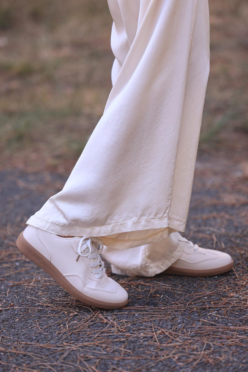 Deportivas finas y ligeras en color blanco roto con suela ligeramente compensada.