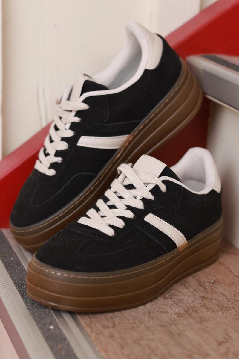 Deportivas de ante negro con plataforma a rayas beige y negras.