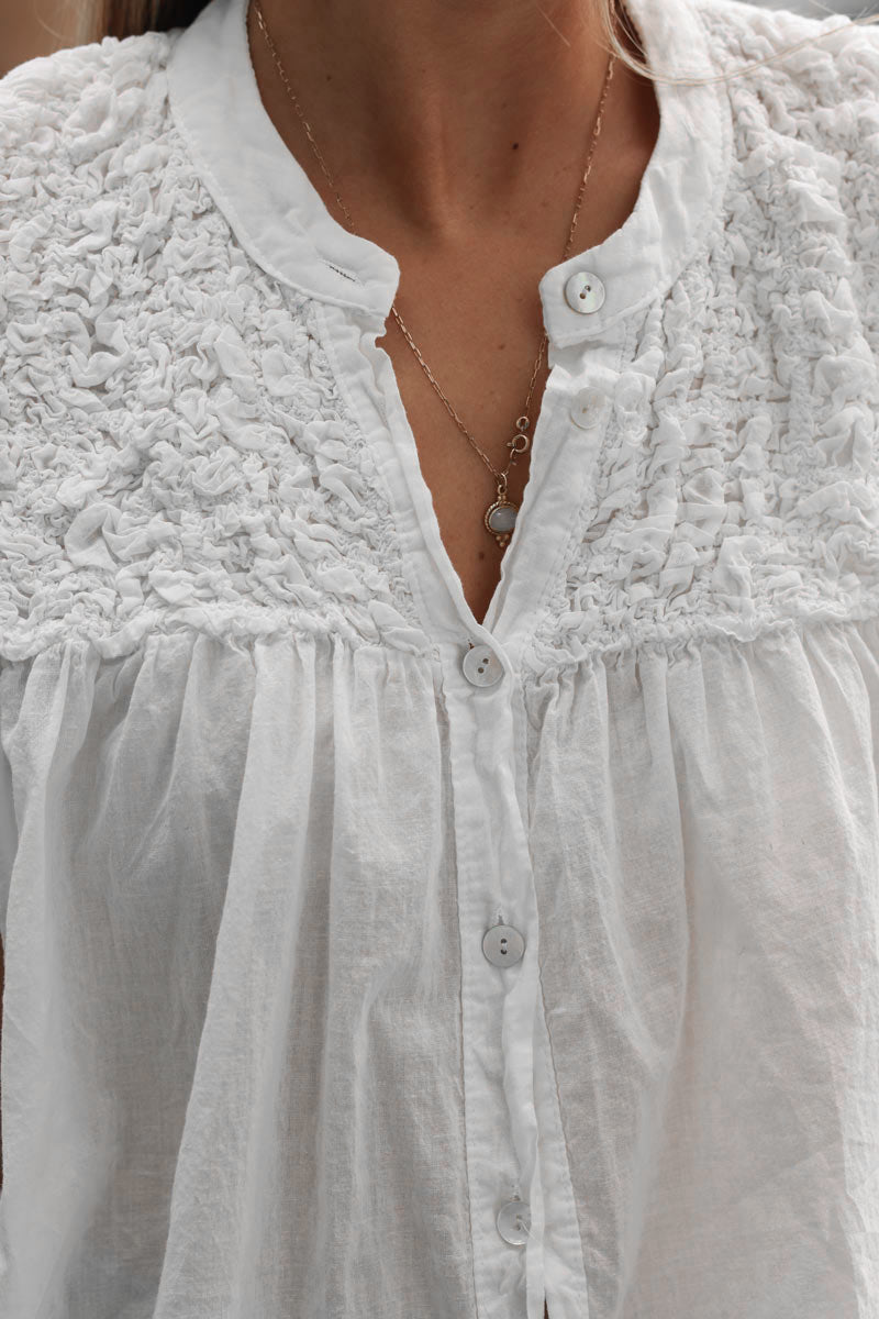 Blusa blanca sin mangas con botones y cuello fruncido