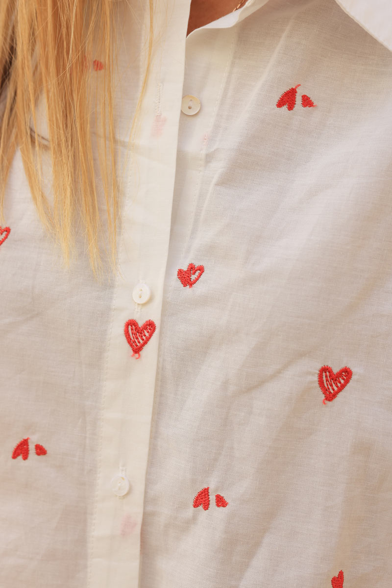 Camisa blanca de algodón con bordado de pequeños corazones rojos.