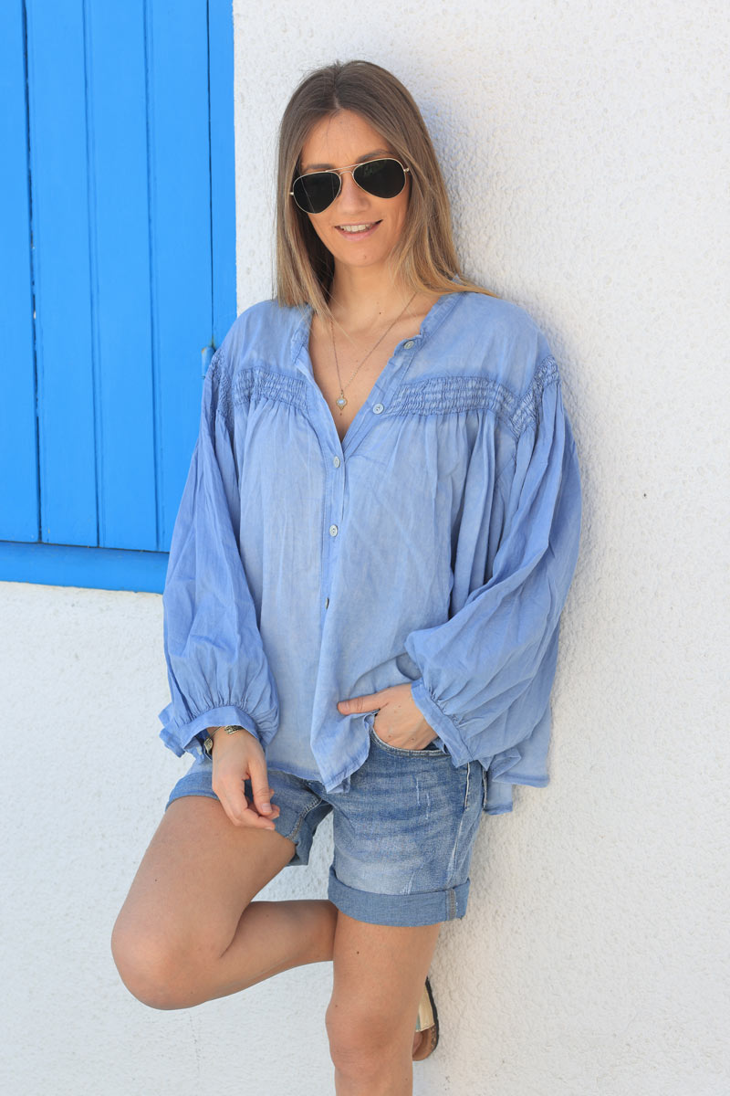 Blusa de algodón denim azul con mangas anchas, botones nacarados y cuello fruncido.