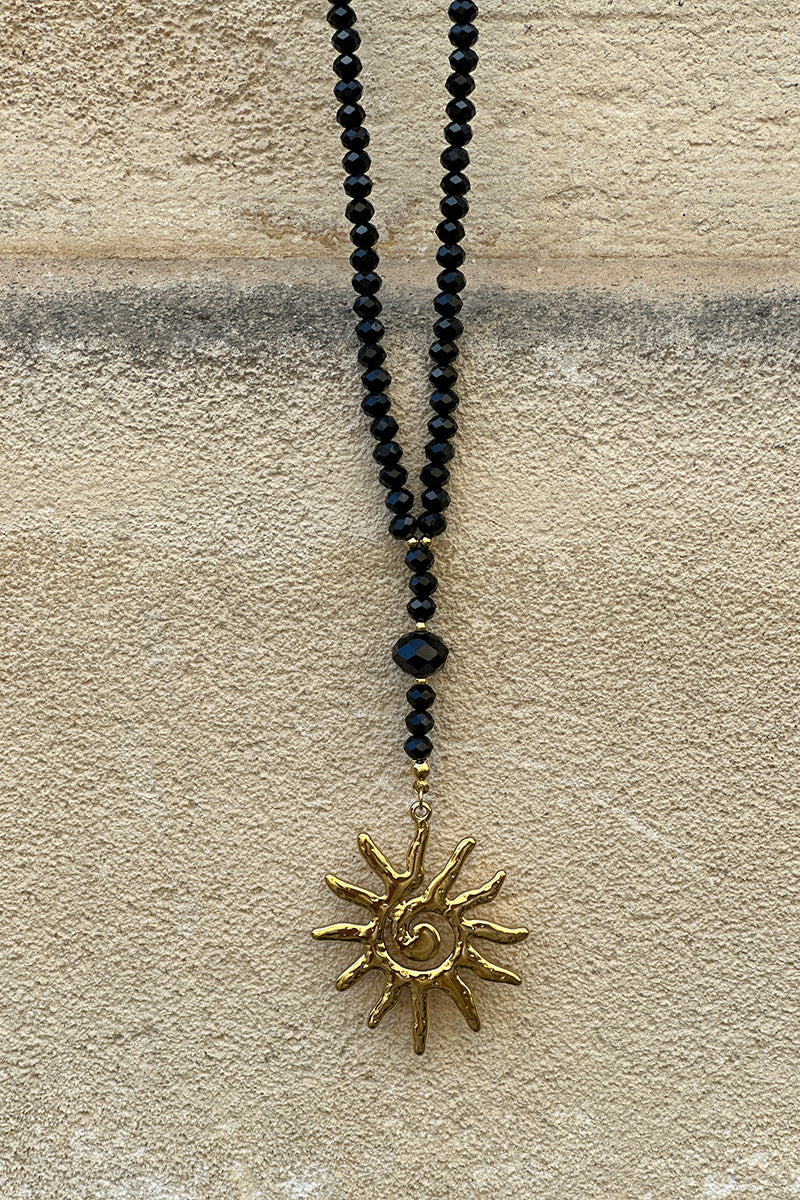 Collier long style sautoir perles facettes noires pendentif soleil doré