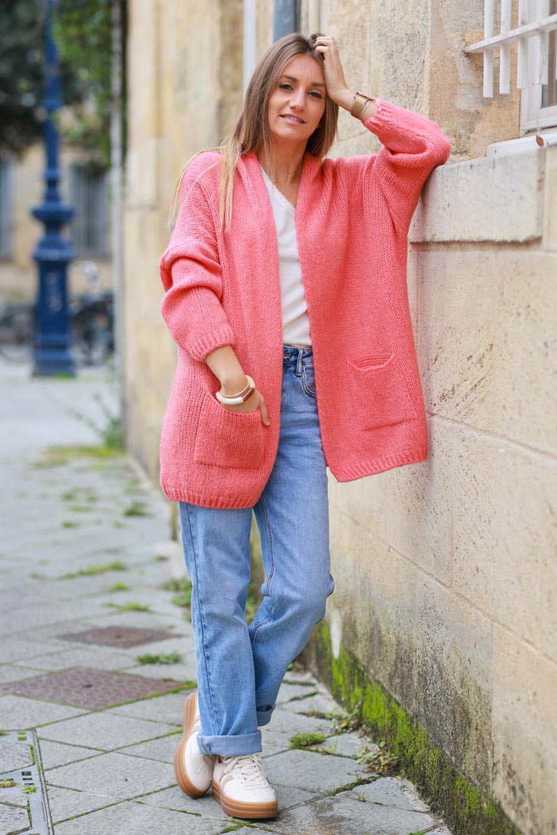 Chaleco coral con cuello cruzado y bolsillos.