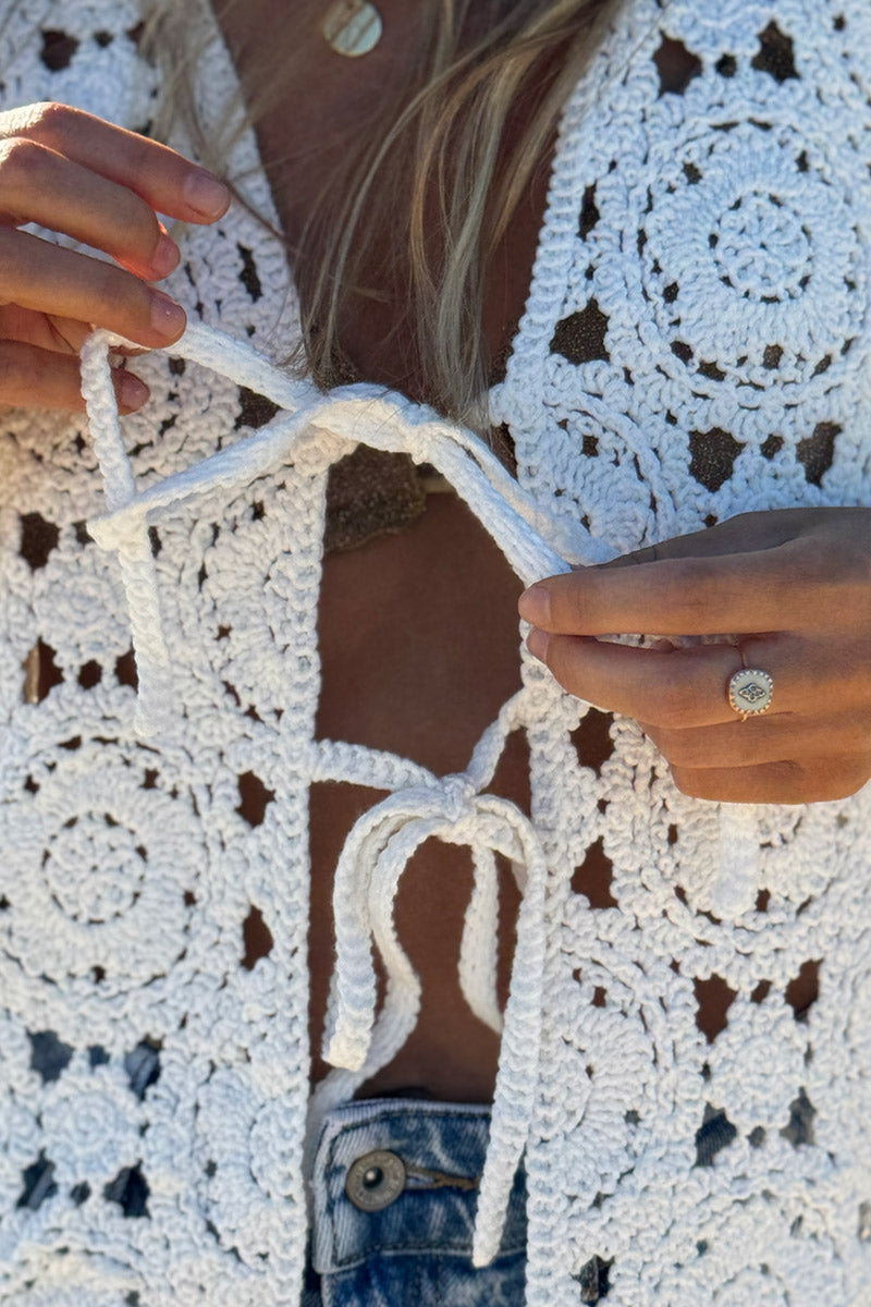 Cárdigan corto sin mangas en color blanco roto de crochet con cierre de lazo pequeño