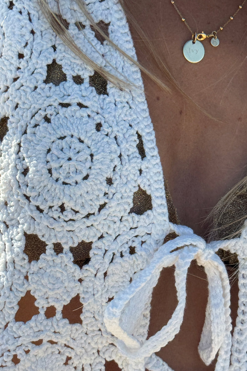 Cárdigan corto sin mangas en color blanco roto de crochet con cierre de lazo pequeño