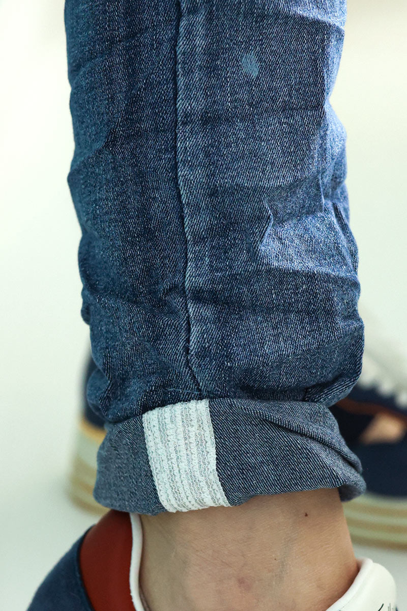 Jeans lavado claro con botones y ribete plateado en los tobillos.