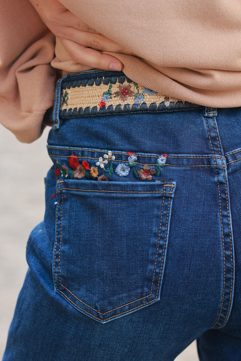 Mid-wash stretch jeans with colorful flower embroidery, pockets, and embroidered raffia belt