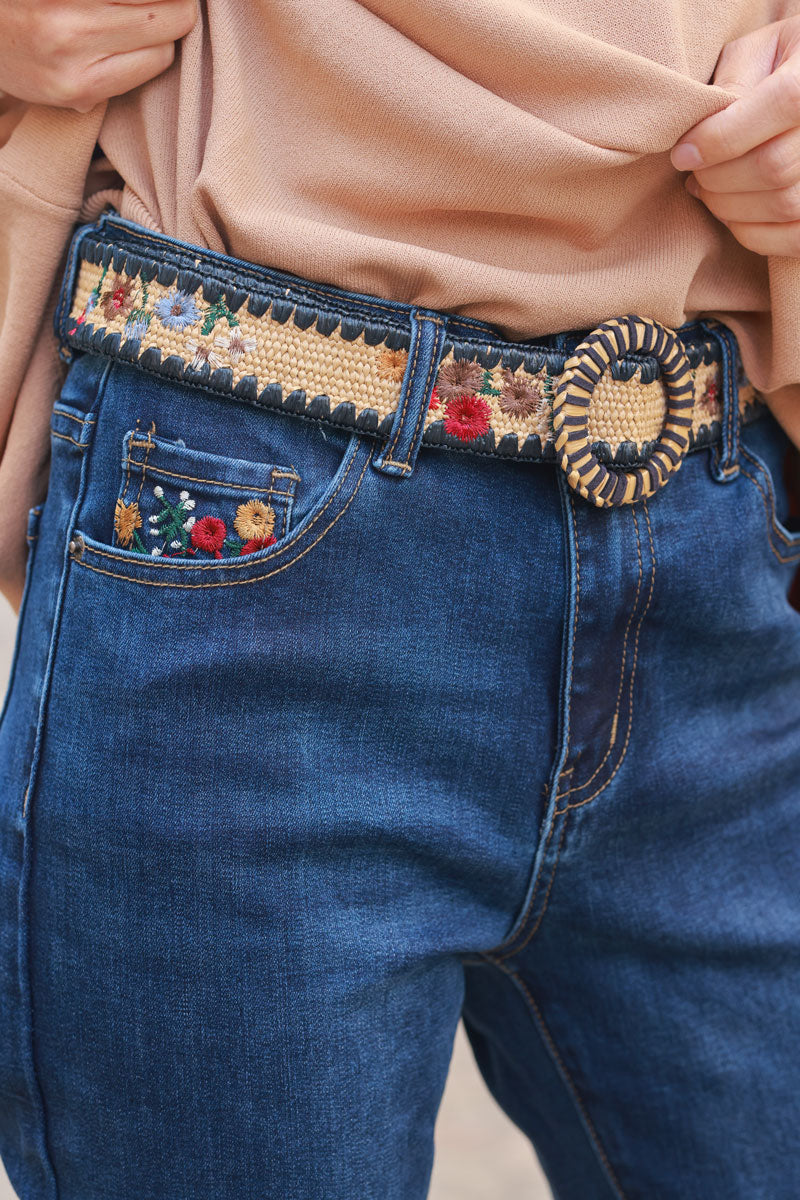 Mid-wash stretch jeans with colorful flower embroidery, pockets, and embroidered raffia belt