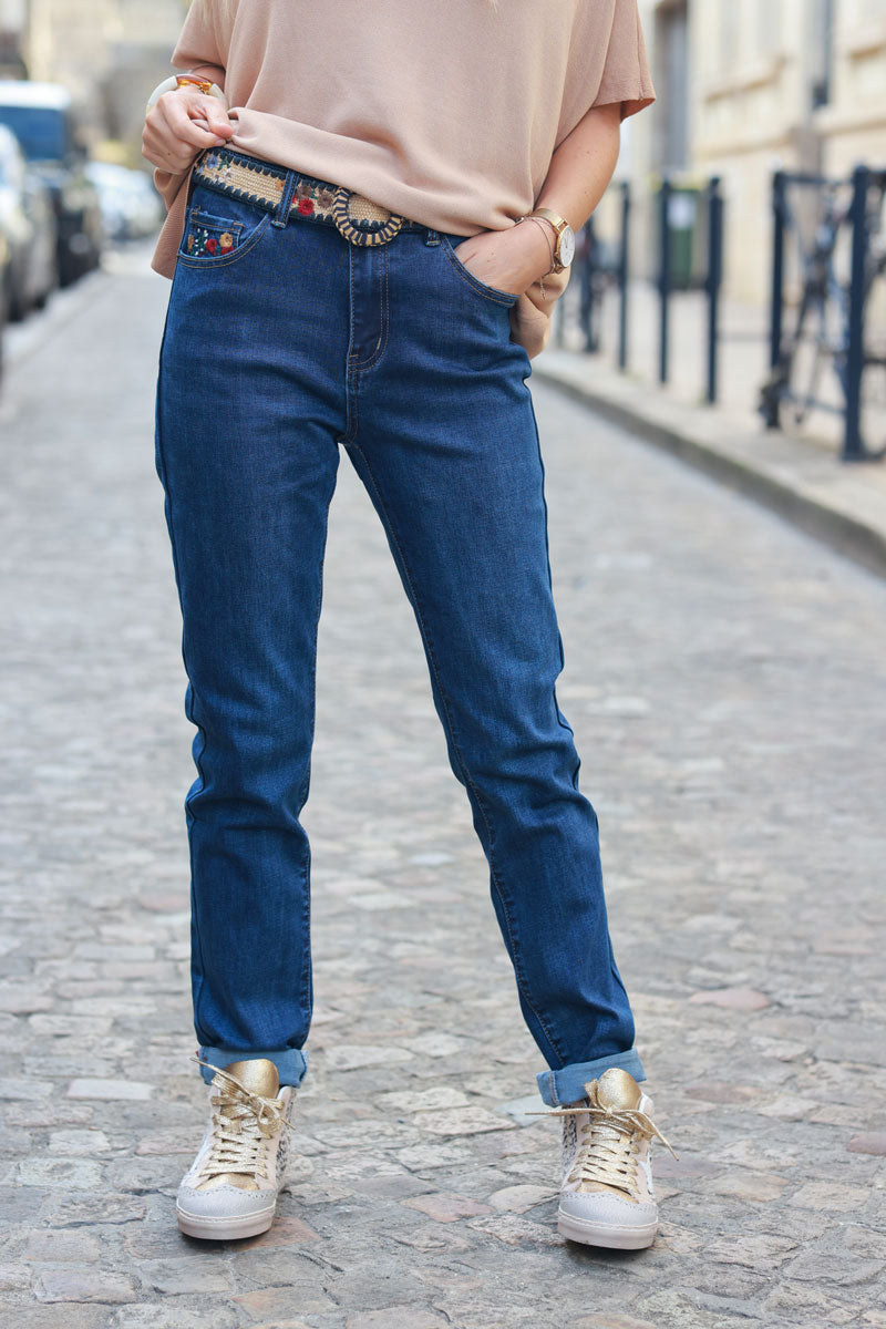 Mid-wash stretch jeans with colorful flower embroidery, pockets, and embroidered raffia belt