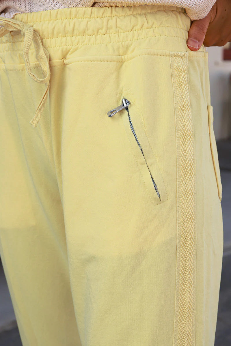 Jogging jaune pâle en coton à ceinture élastique, poches zippées et liseré broderie chevrons