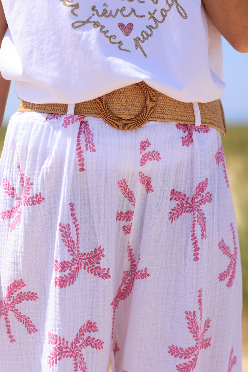 Pantalon en gaze de coton blanc imprimé palmiers fuchsia effet broderie avec ceinture raphia