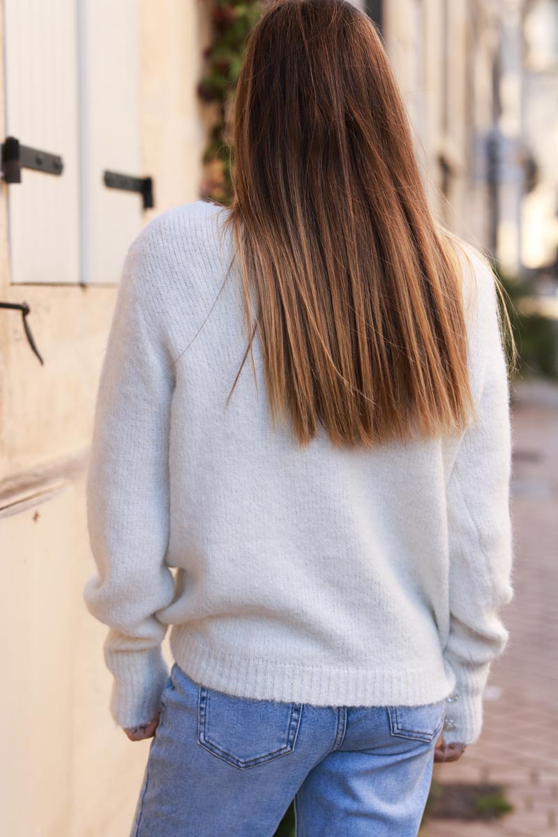 Suéter de punto suave y acogedor en color blanco roto con cuello en V, mangas fruncidas y botones de flores