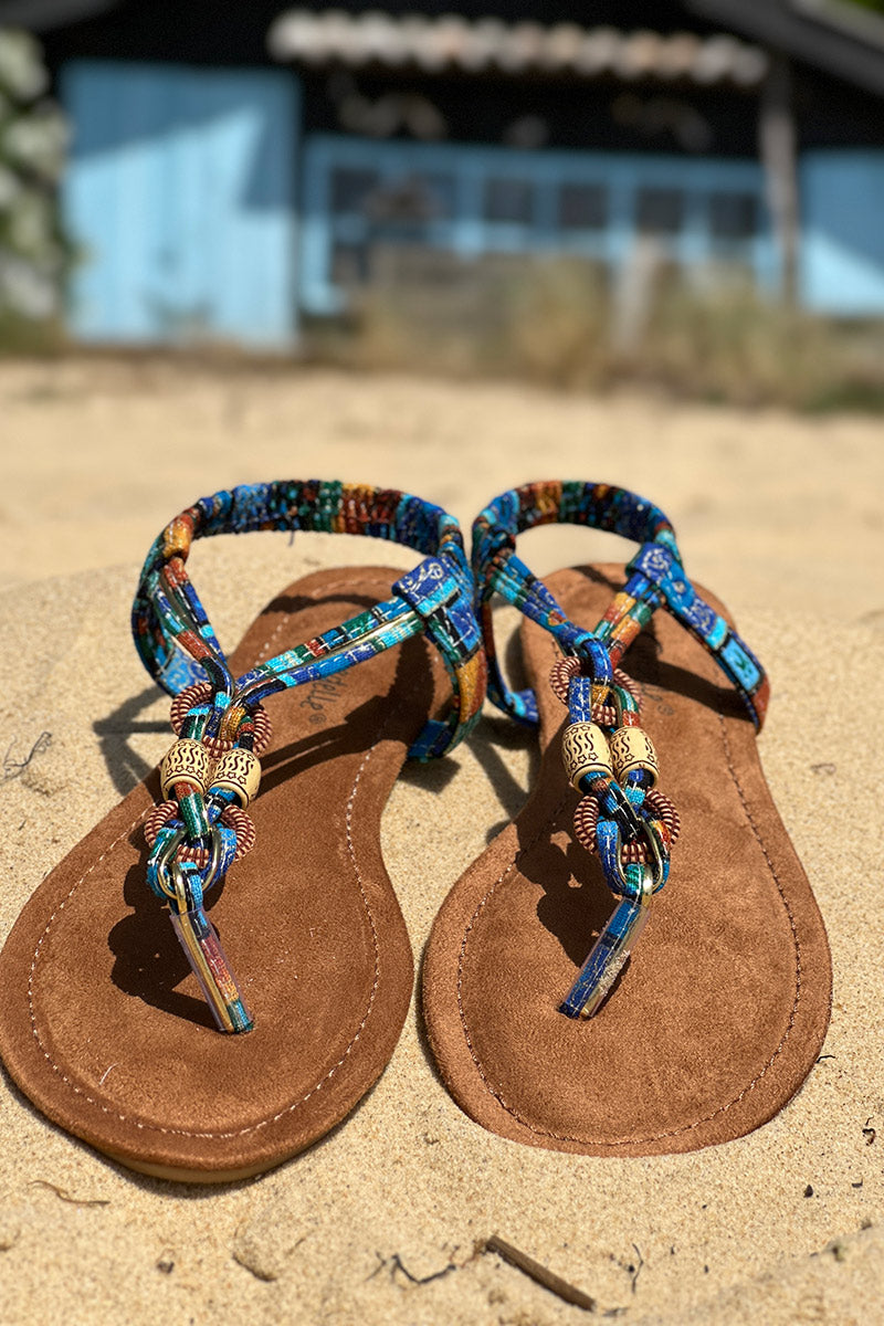 Sandalias tipo chanclas de tejido estampado encerado azul con perlas y detalles dorados