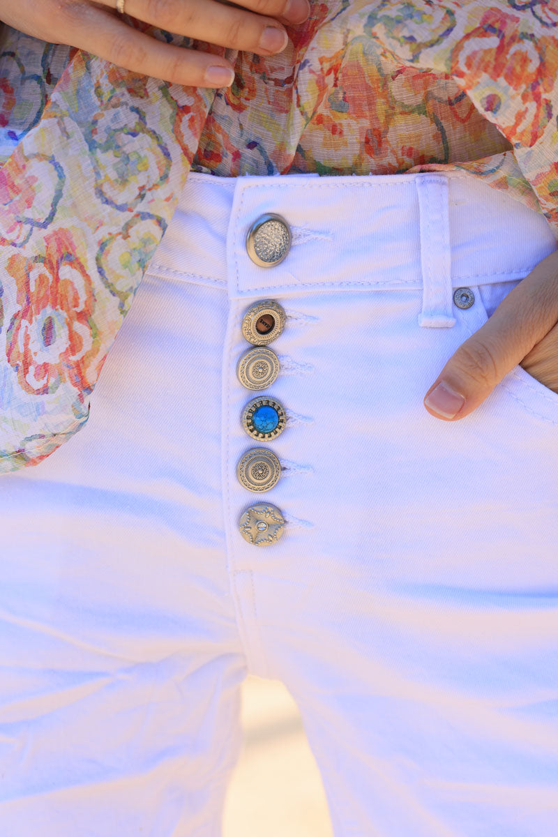 Pantalón corto elástico blanco con fantasía de strass y botones turquesas.