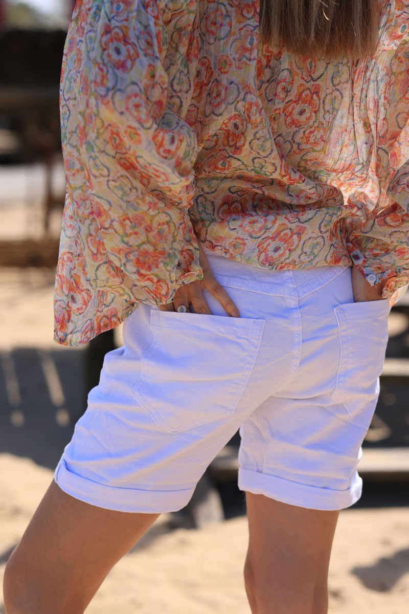 Pantalón corto elástico blanco con fantasía de strass y botones turquesas.