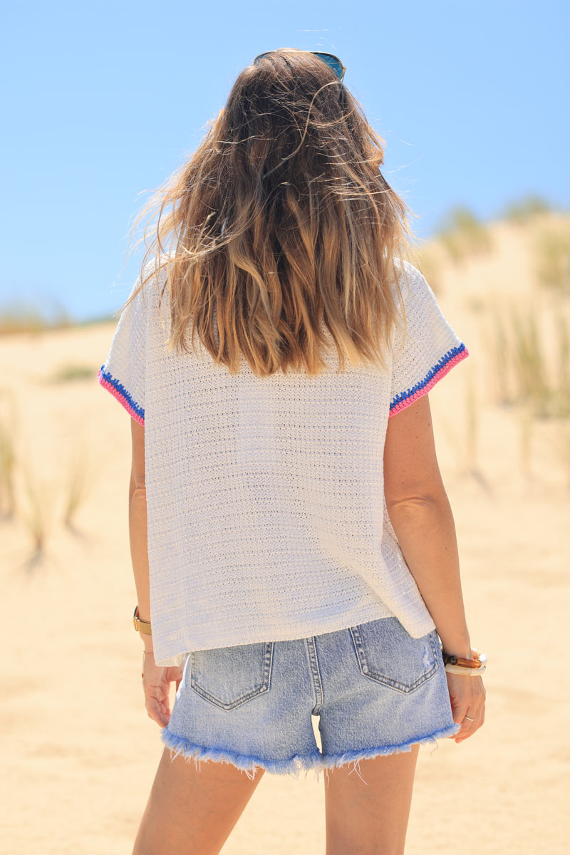 Top de crochet blanco con manga corta y flores de colores.