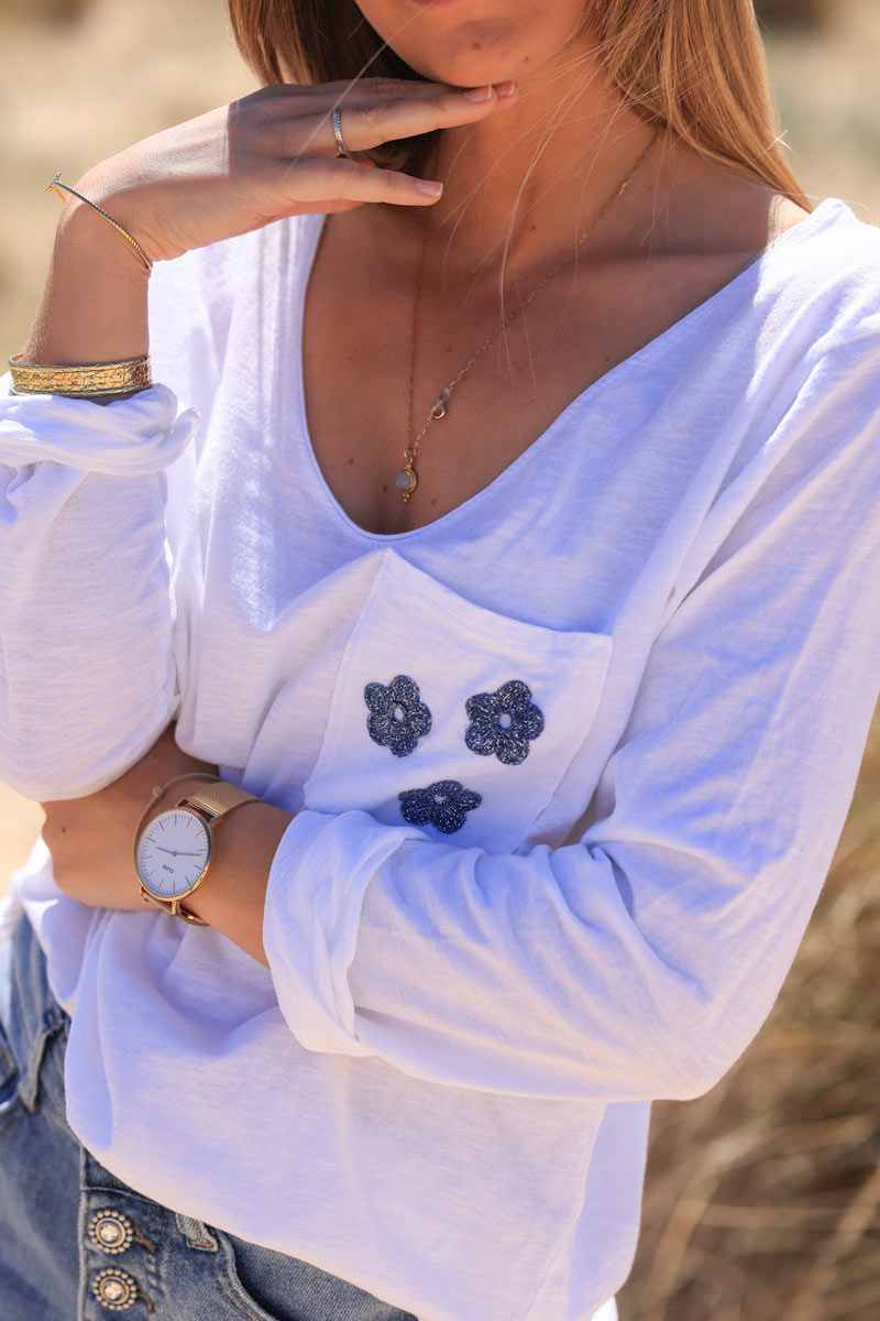 White long sleeve top with blue embroidered pocket flowers