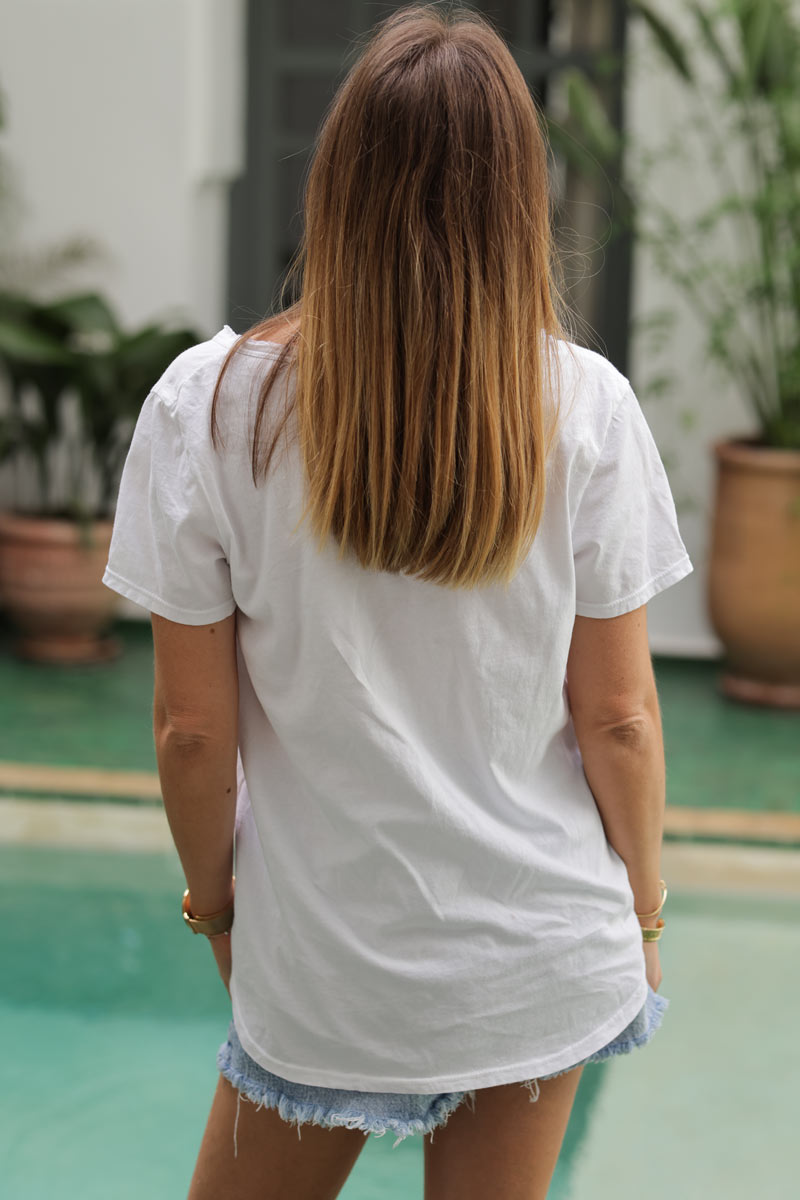 Camiseta blanca de algodón con cuello de pico y bordado de margaritas celestes