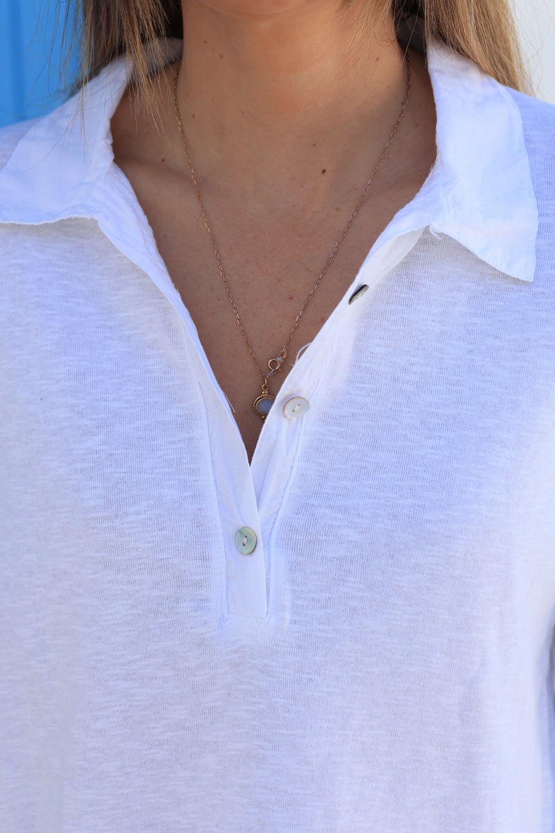 Camiseta blanca de algodón de manga larga con cuello camisero y pequeños botones.