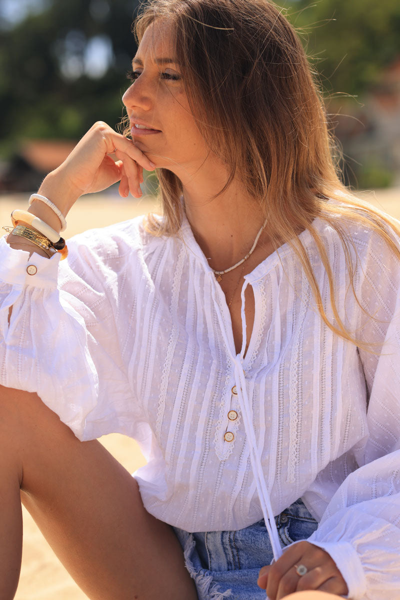 Túnica blanca con plumetis y encaje de rayas, cuello con botones y pompones