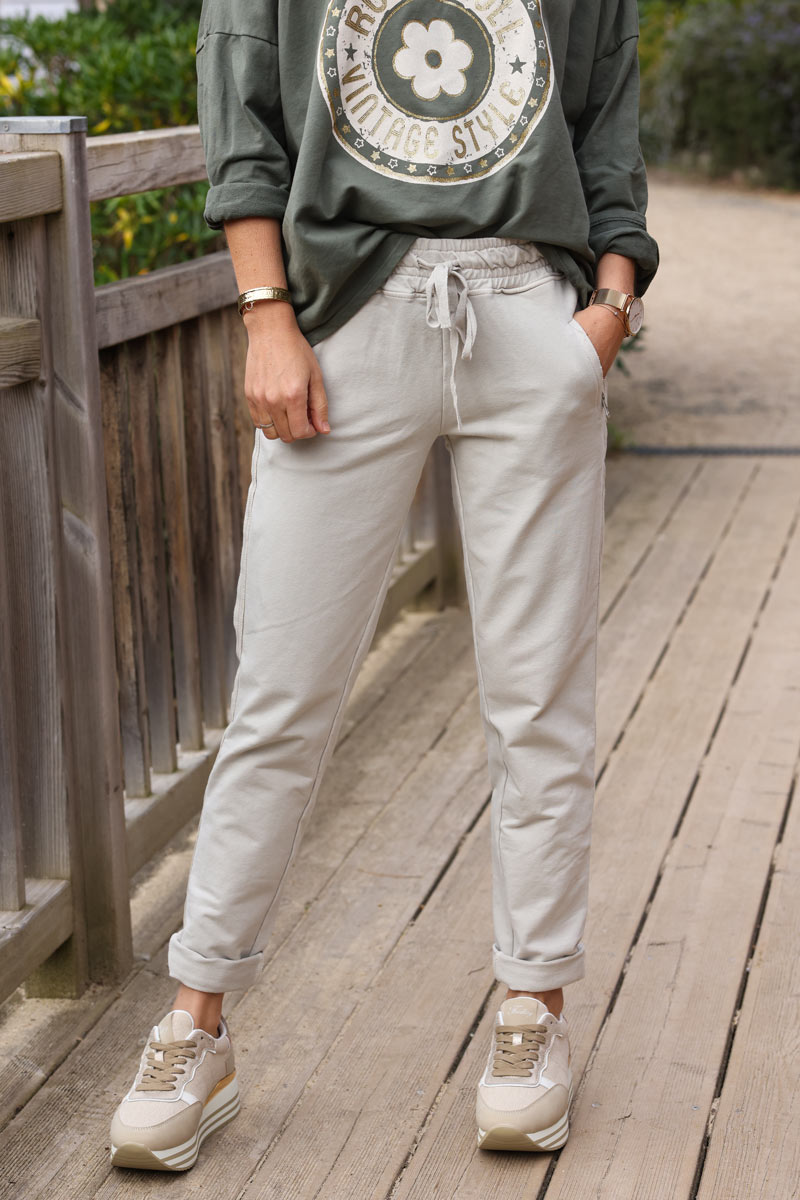 Pantalón jogging beige con ribete de cinta en los bolsillos laterales con cremallera cinturilla elástica